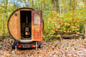 Fasssauna mieten Badefass mieten. Eine Fasssauna steht im Wald.